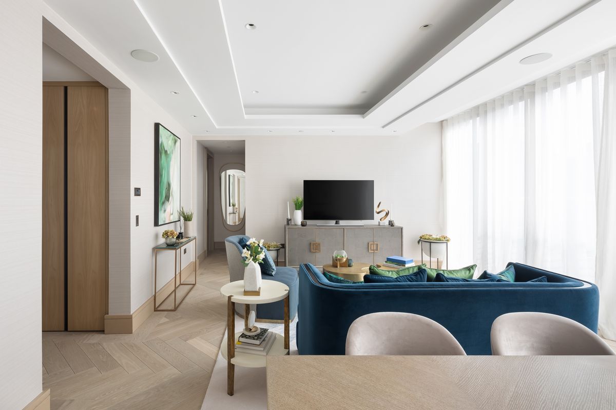 Bright open-plan living room with blue velvet sofa, herringbone oak floor and sheer curtains – Chiltern Place by PLP Architecture. Photograph by Daniel Avery.