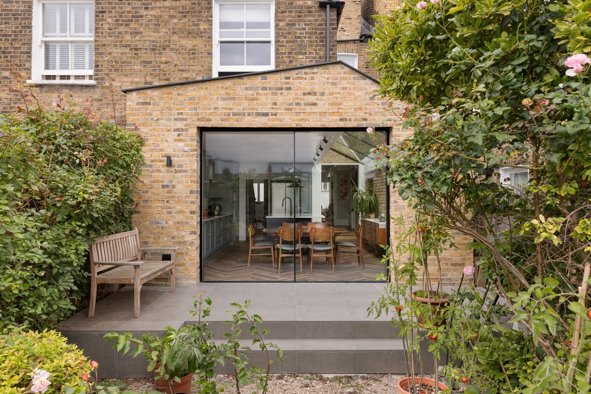 Rear extension with slim steel-framed glazing opening onto a planted garden terrace – Parolles Road by Patrick Crowe Architects. Photograph by Daniel Avery.