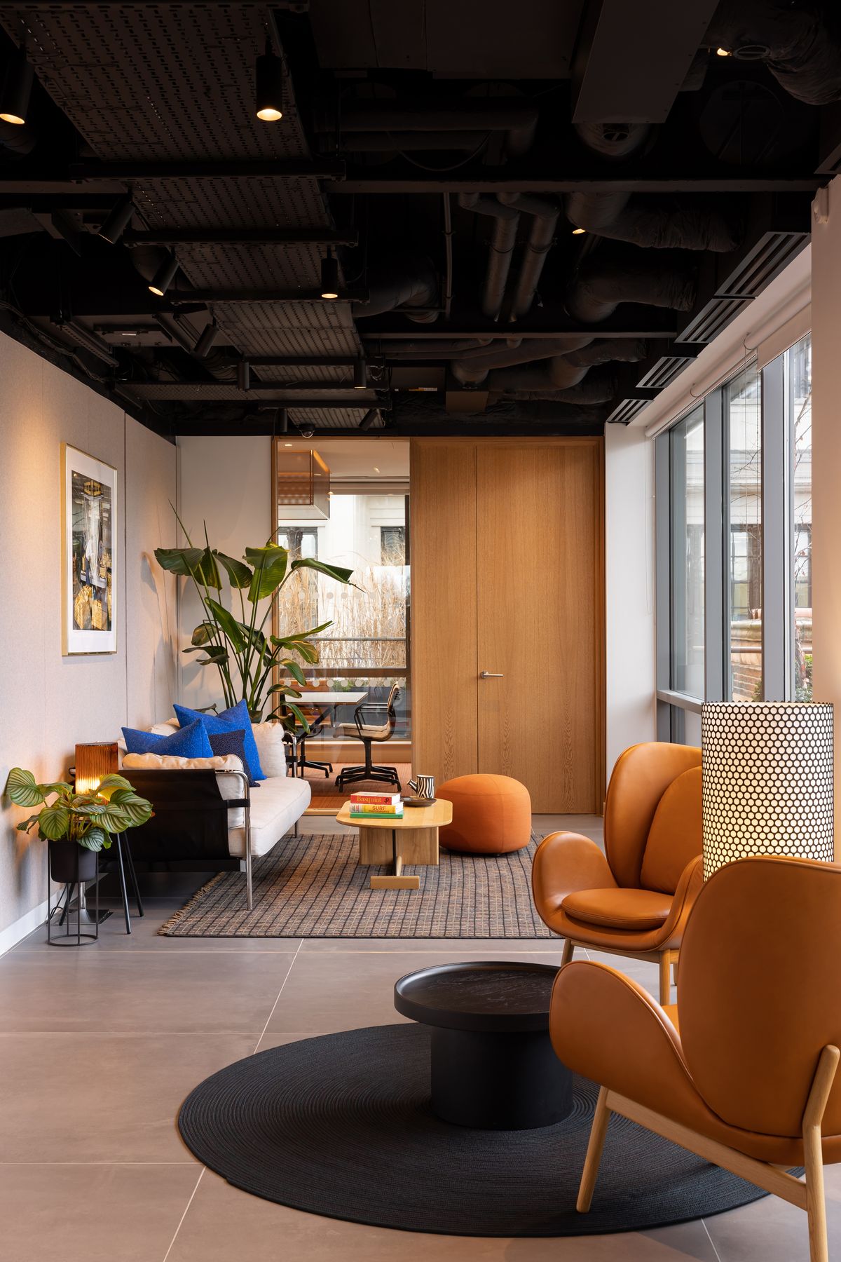 Office breakout lounge with tan leather chairs under an exposed black ceiling – Endeavour Offices by Studio Von B. Photograph by Daniel Avery.