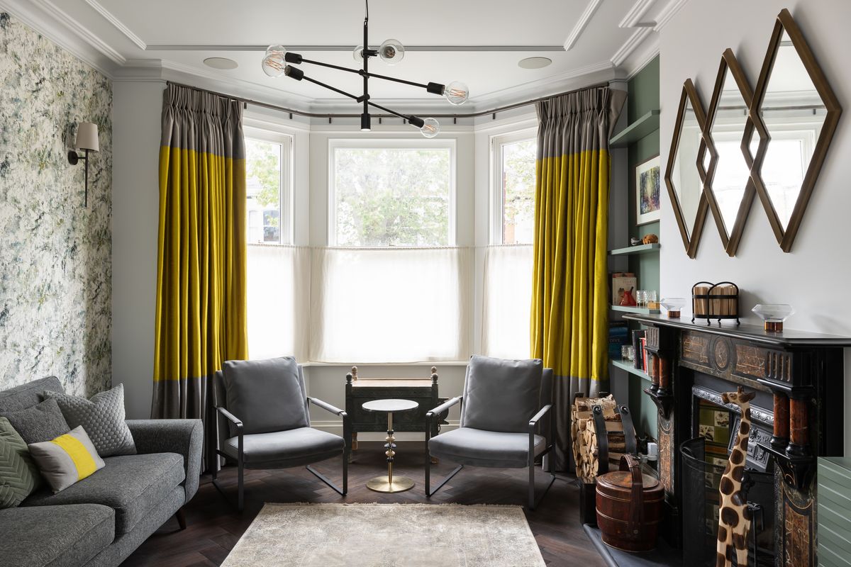 Victorian bay-window sitting room with mustard curtains and cast-iron fireplace – Chevening Road by Hone Studio. Photograph by Daniel Avery.